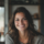 Femme souriante, cheveux bruns, intérieur lumineux.